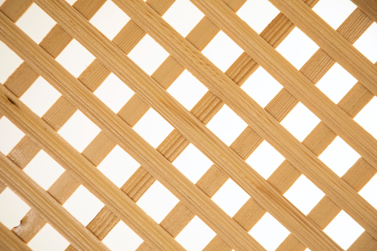 Motif de lattes de bois entrecroisées formant un treillis.