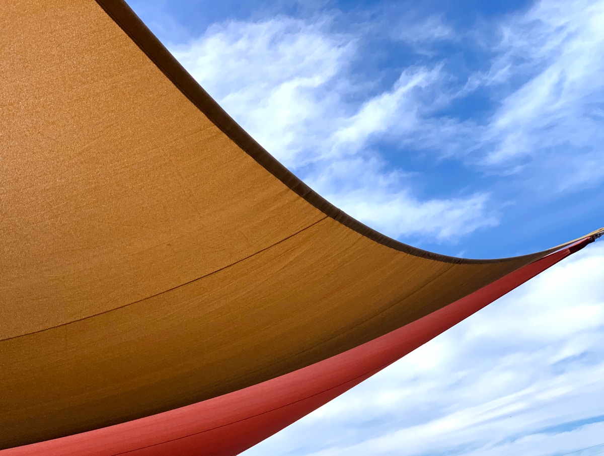 Voile jaune et rouge contre un ciel bleu nuageux.
