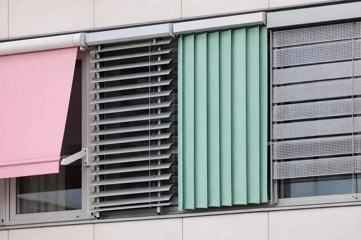 Modern building facade with four different types of exterior sun protection systems installed on adjacent windows, showing screen blinds, zip systems, awnings and vertical blinds in contemporary architecture, clear daylight, professional installation detail, no text or labels
