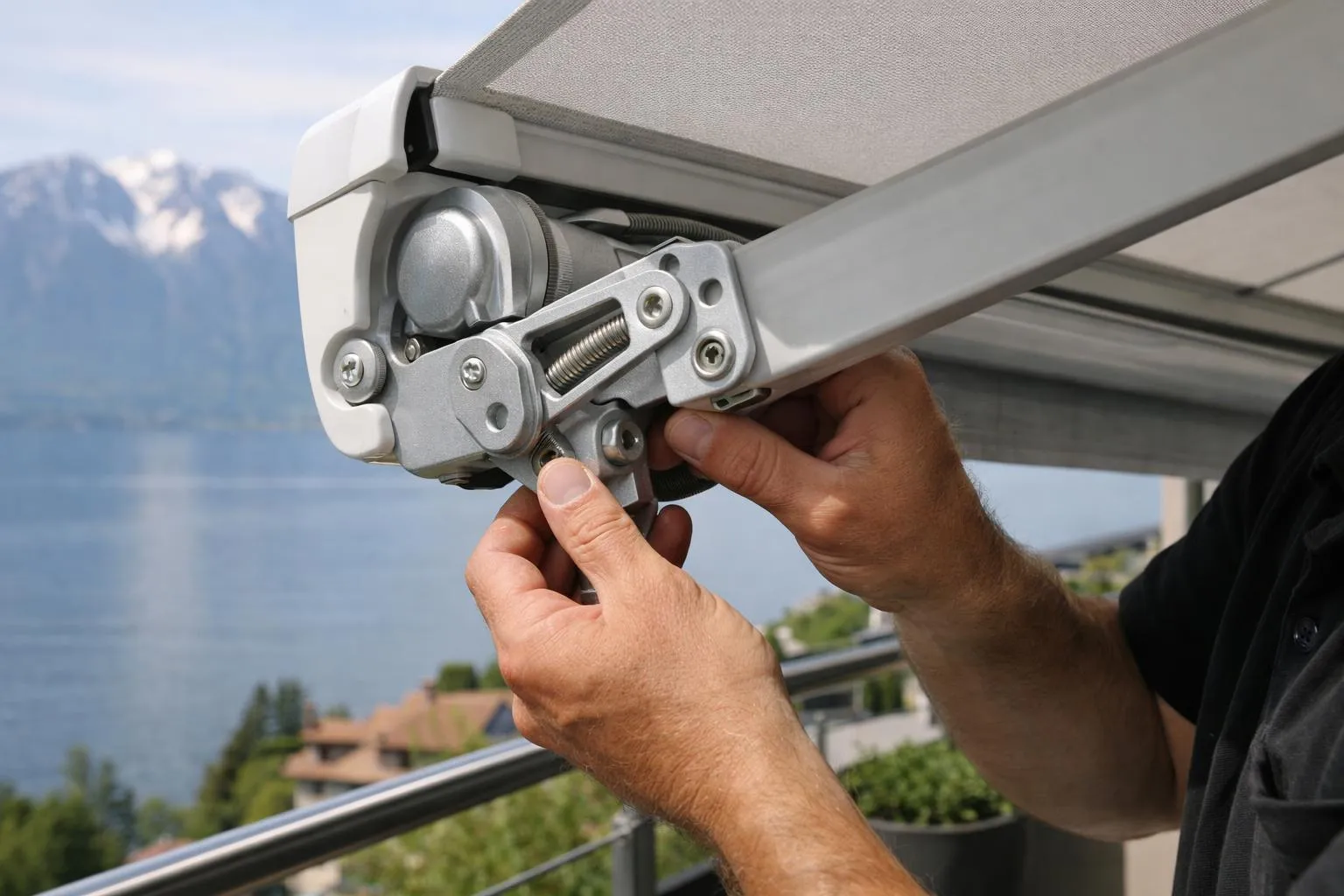 Close-up of a high-quality projection awning arm mechanism being inspected by a professional installer's hands on a Swiss residential balcony, showing aluminum brackets and tension springs with Lake Geneva visible in the background, natural daylight, realistic photography style emphasizing craftsmanship and local expertise