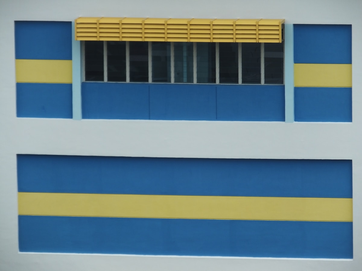 Bâtiment avec fenêtres et façade bleue et jaune.