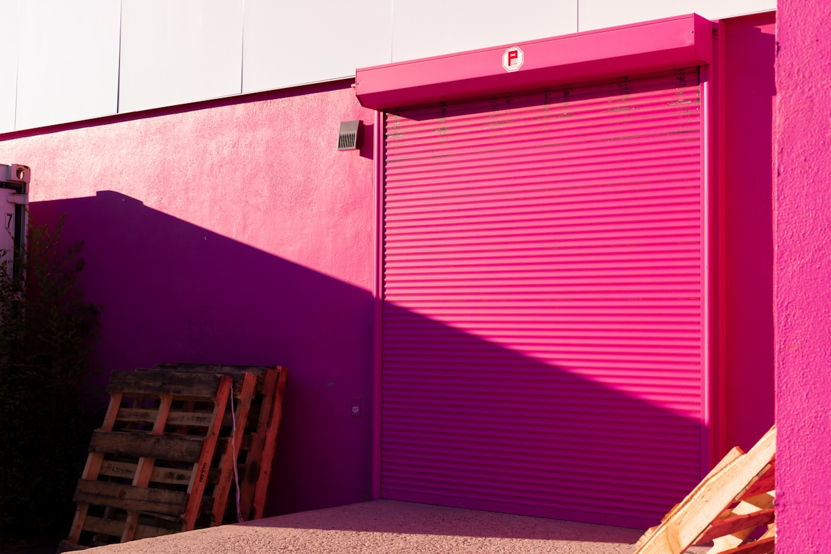 Rideau métallique rose vif sur un mur violet.