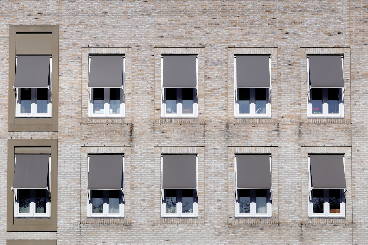 Façade de briques avec fenêtres à stores gris.