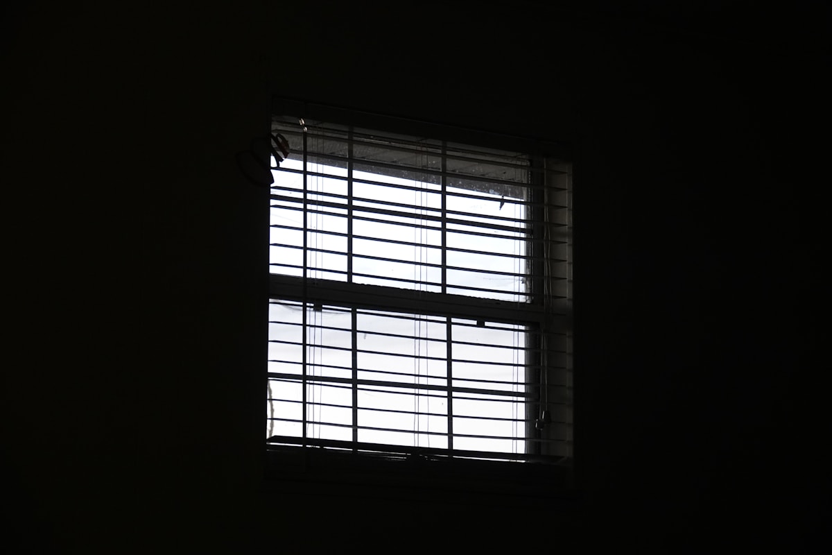 Une fenêtre dans une pièce sombre avec de la lumière qui passe à travers.