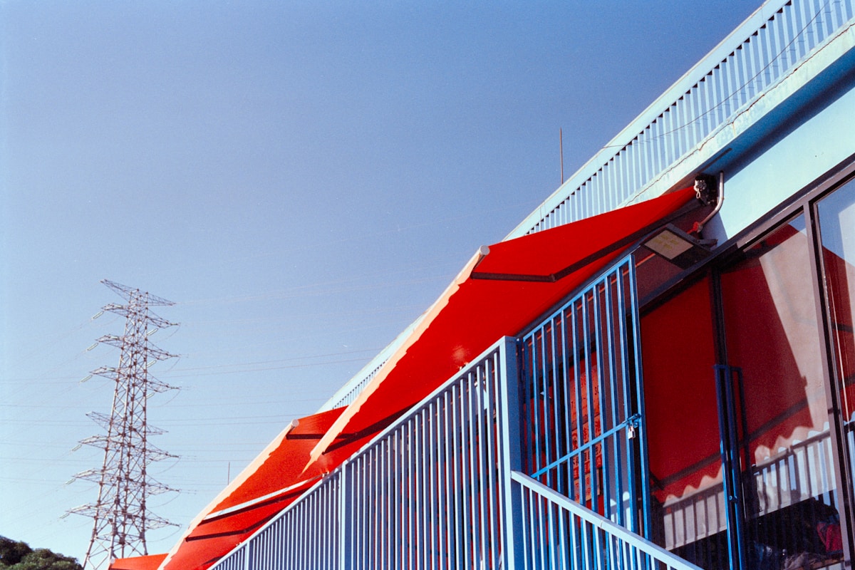 Bâtiment industriel rouge et blanc avec pylône électrique.
