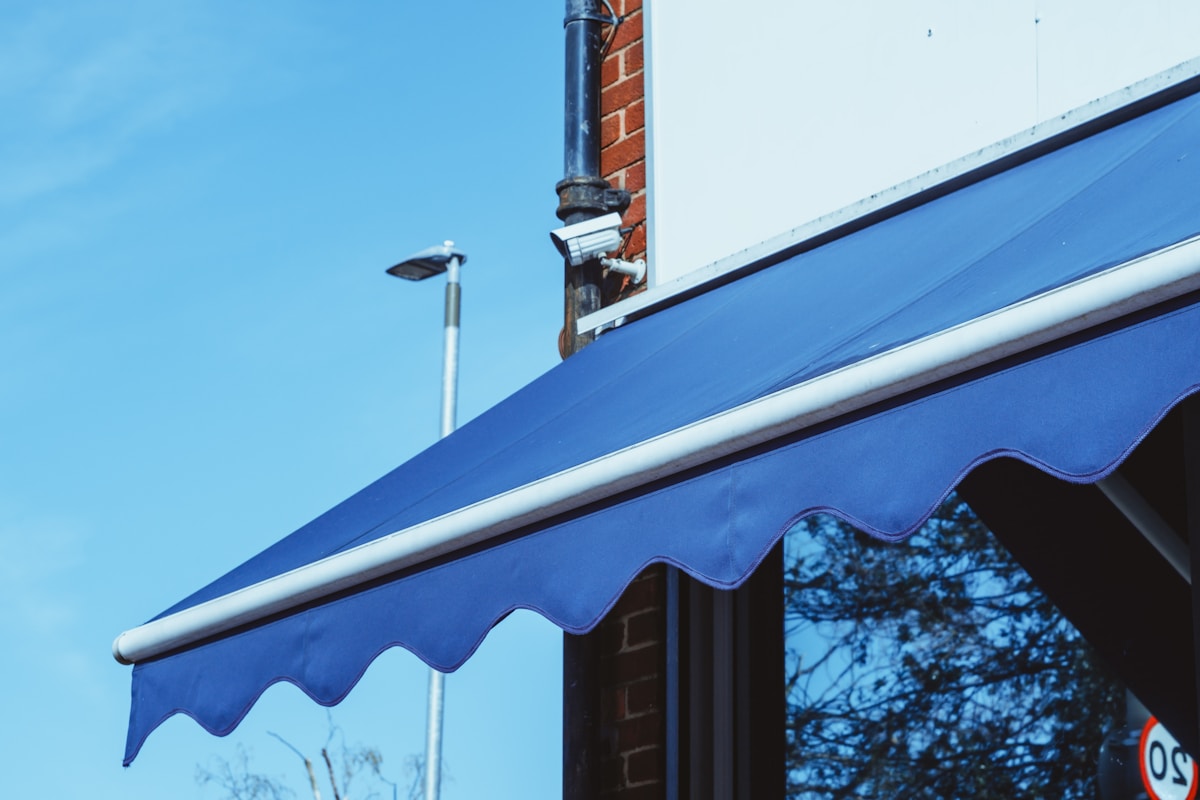 Auvent bleu ondulé sur un bâtiment avec un tuyau de cheminée.