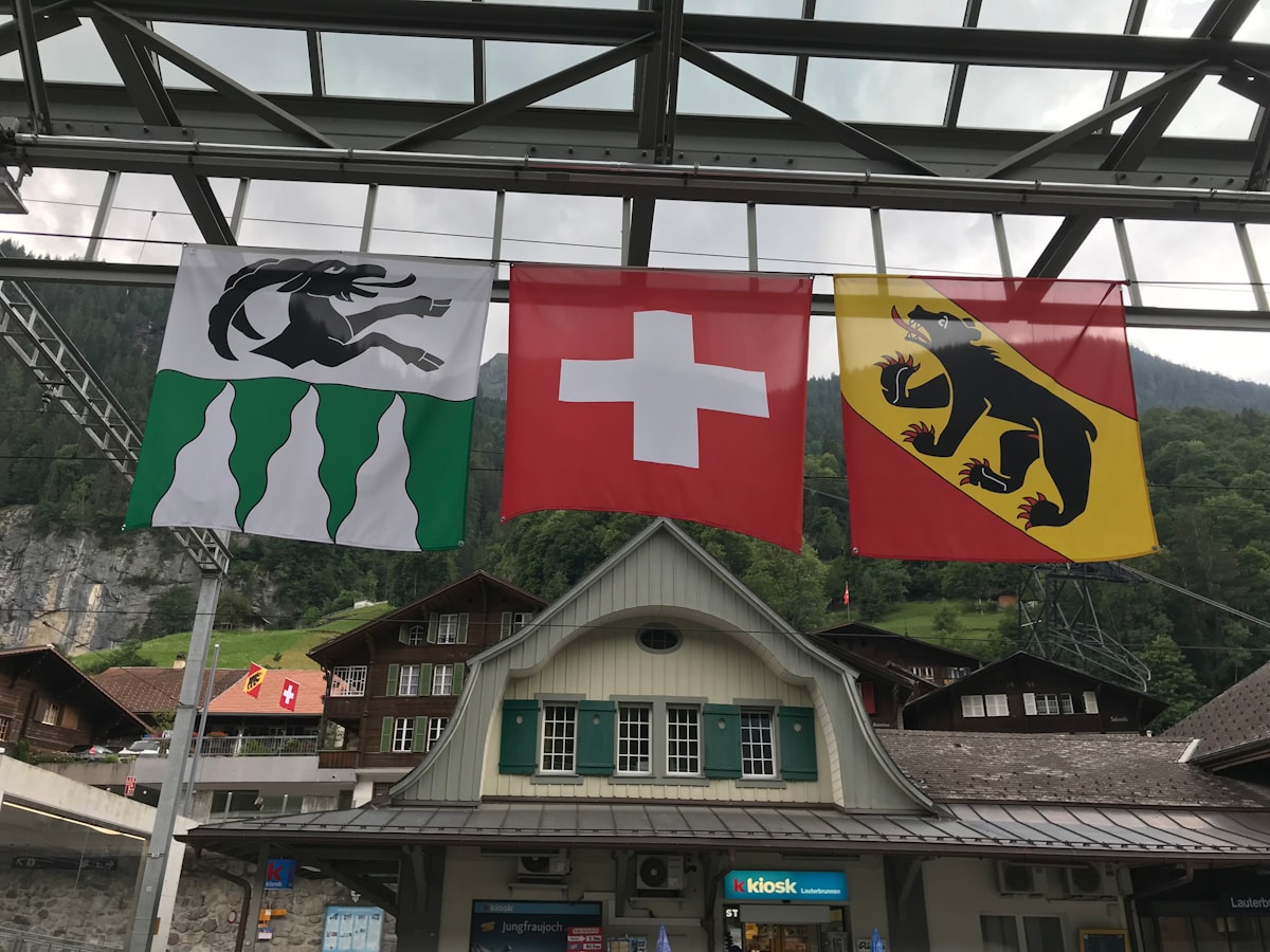 Drapeaux suisses et cantonaux flottant au-dessus d'un bâtiment alpin.