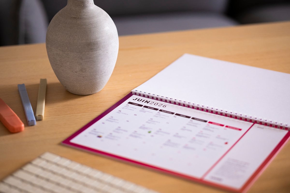 Un calendrier et un vase posés sur un bureau en bois.