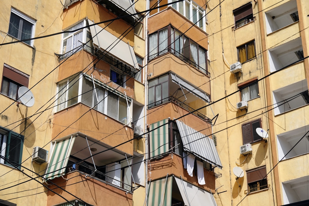 Bâtiment résidentiel ancien avec balcons et câbles électriques.