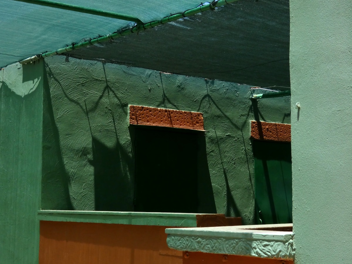 Murs verts texturés avec détails en bois et éléments suspendus.