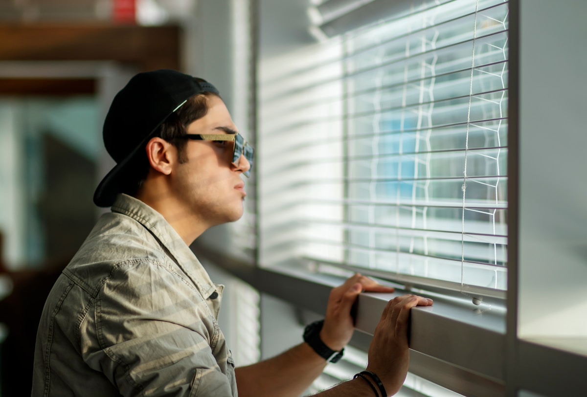 Homme en veste grise regardant par la fenêtre.