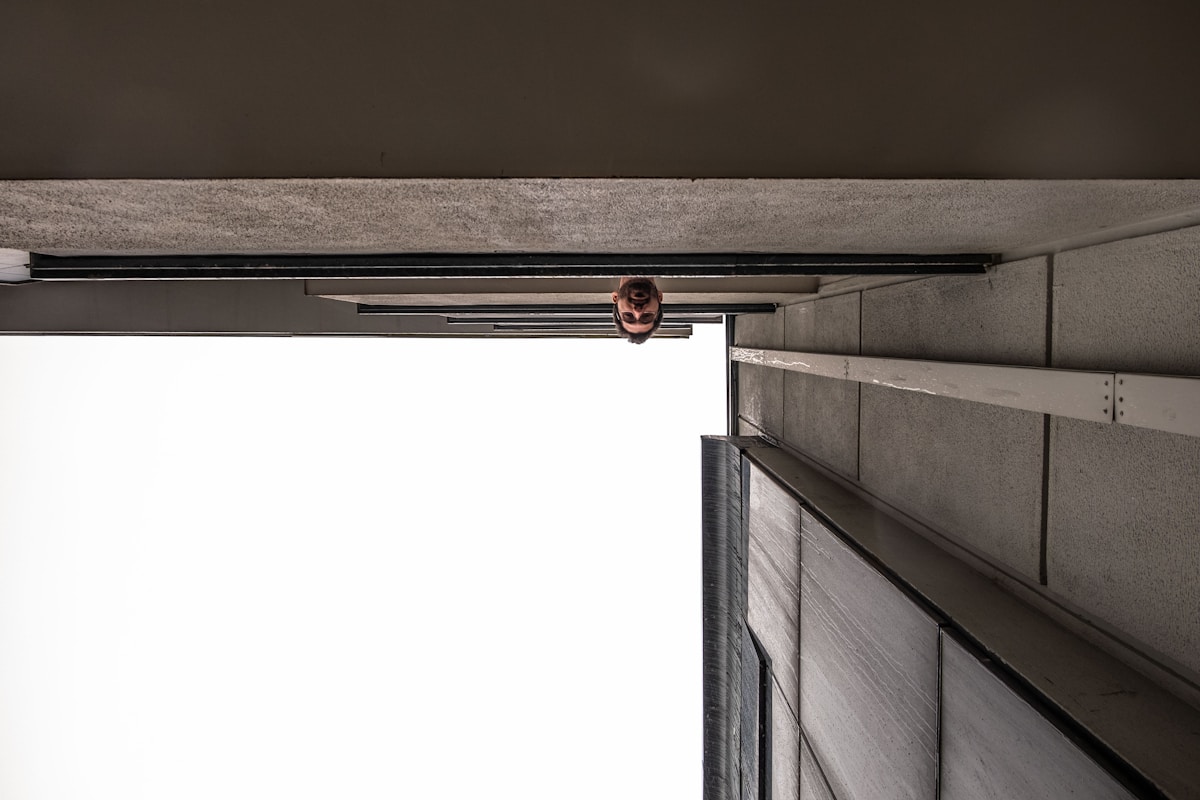 Une personne debout sur un rebord, regardant par la fenêtre.