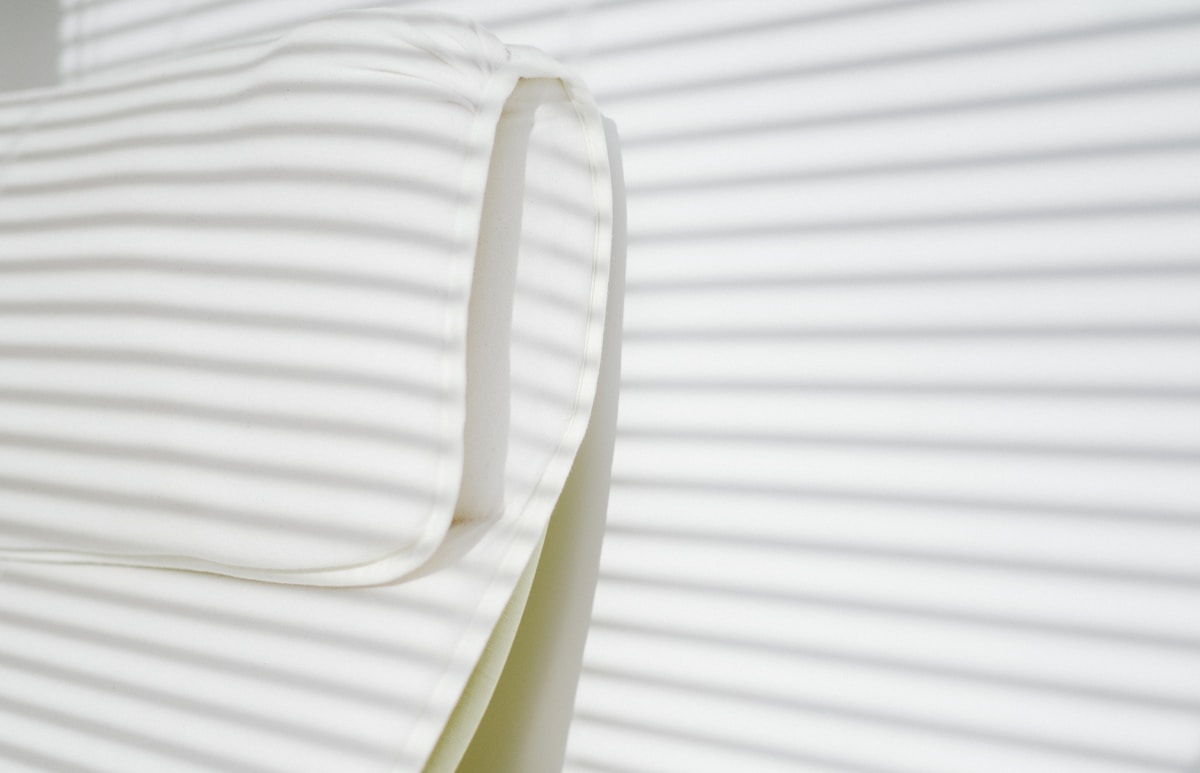 Plis ondulés de tissu blanc, texture douce et élégante.