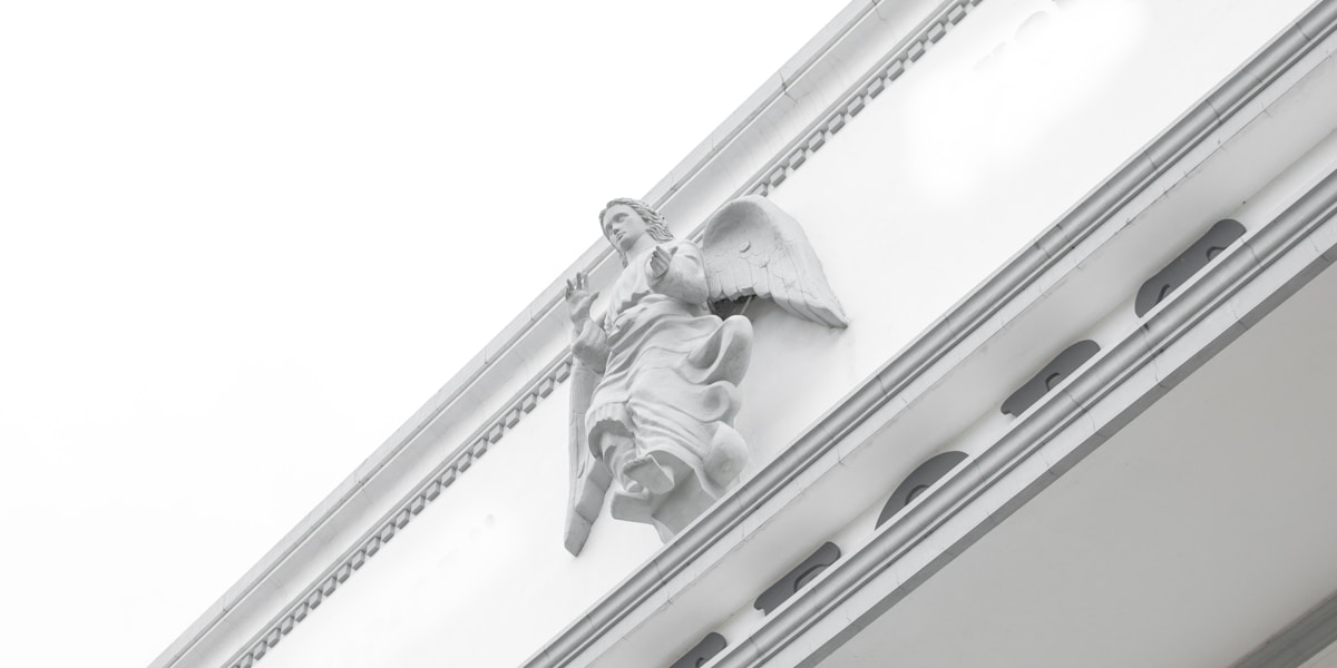 Statue d'un ange en pierre blanche sur un bâtiment.