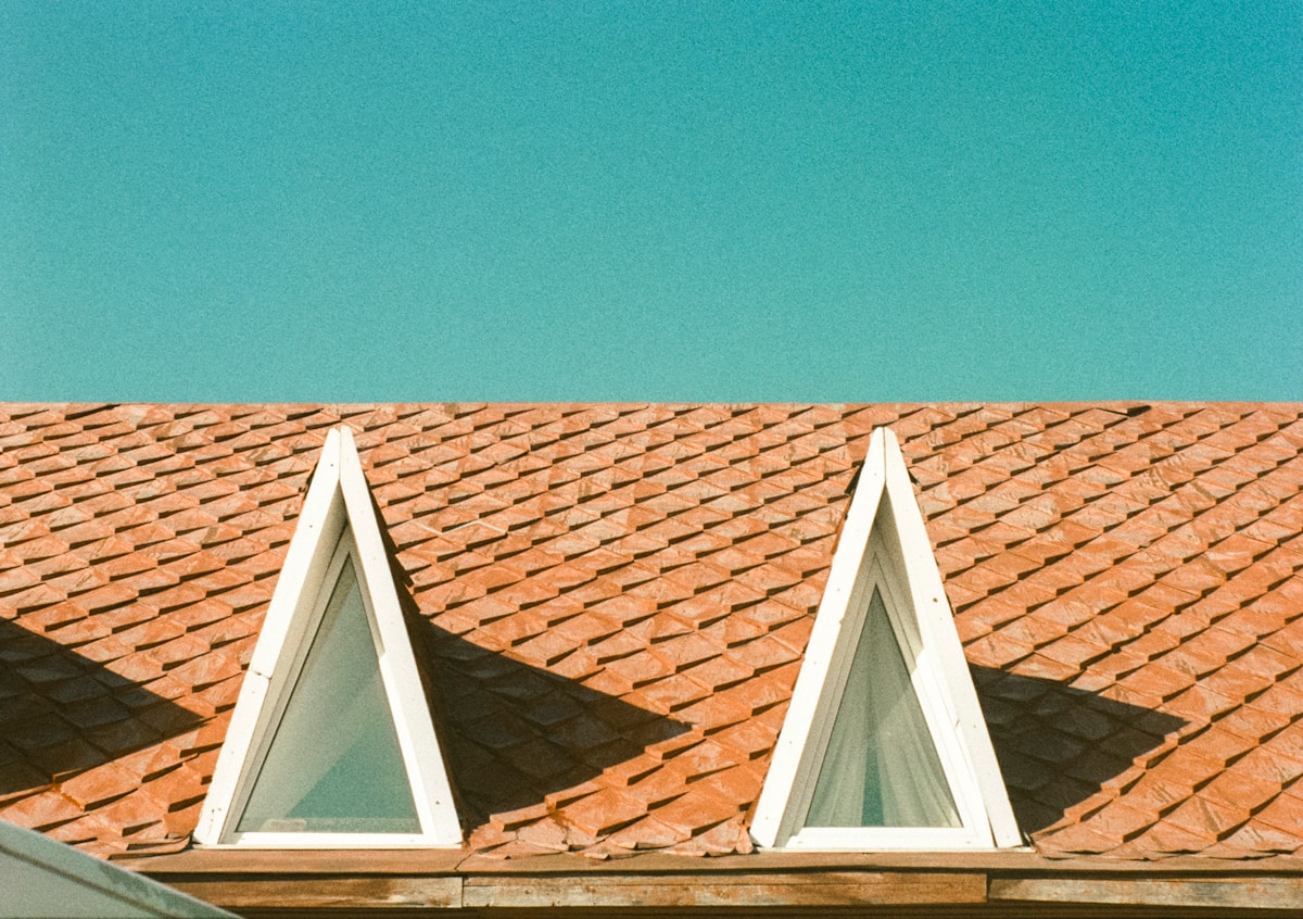 Toiture en tuiles rouges avec fenêtres triangulaires.