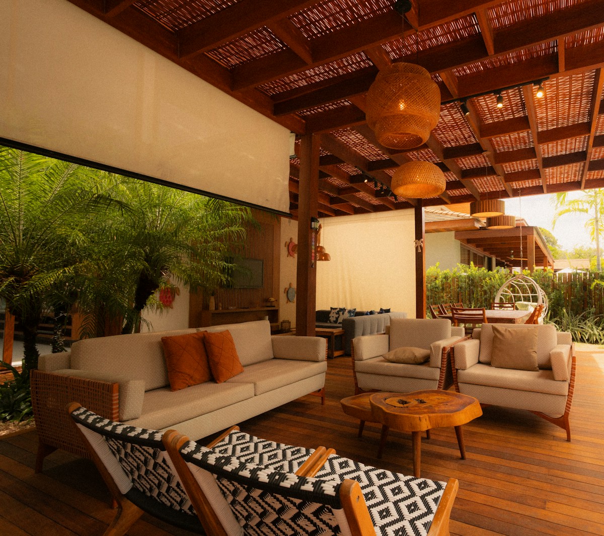 Salon tropical avec mobilier en bois et luminaires en osier.