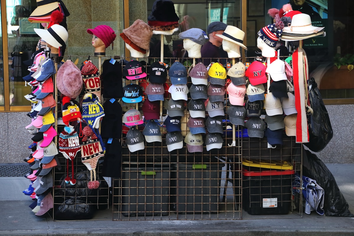 Un vendeur de rue proposant des chapeaux et casquettes en étalage.