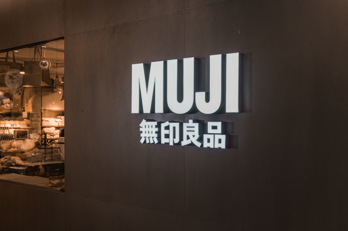 Logo Muji sur un mur sombre avec des caractères japonais