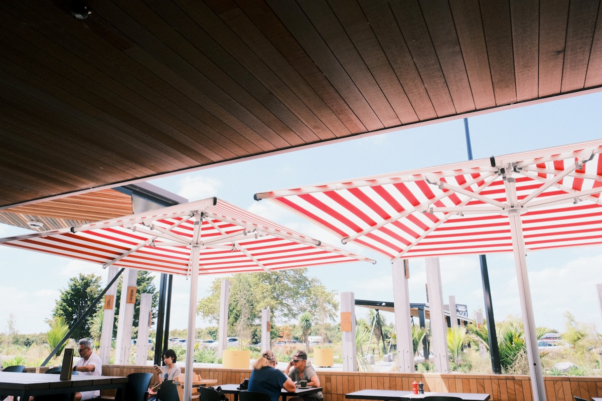 Terrasse couverte avec parasols rayés rouges et blancs.