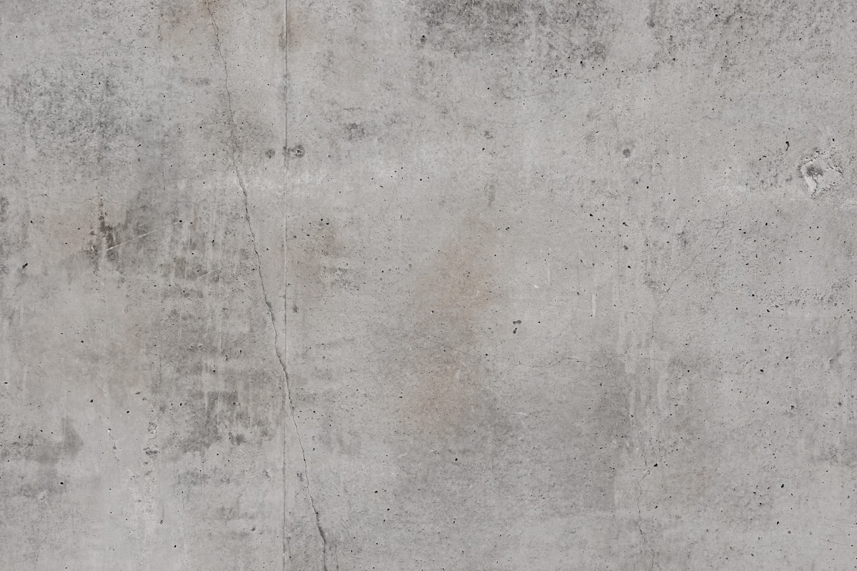 Texture de béton gris foncé avec des fissures et des taches.