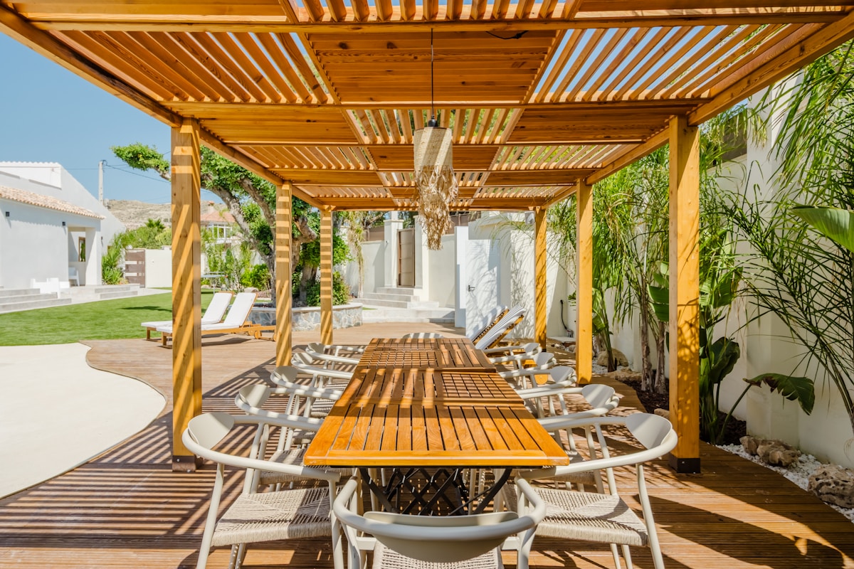 Terrasse en bois avec mobilier de jardin et plantes tropicales.