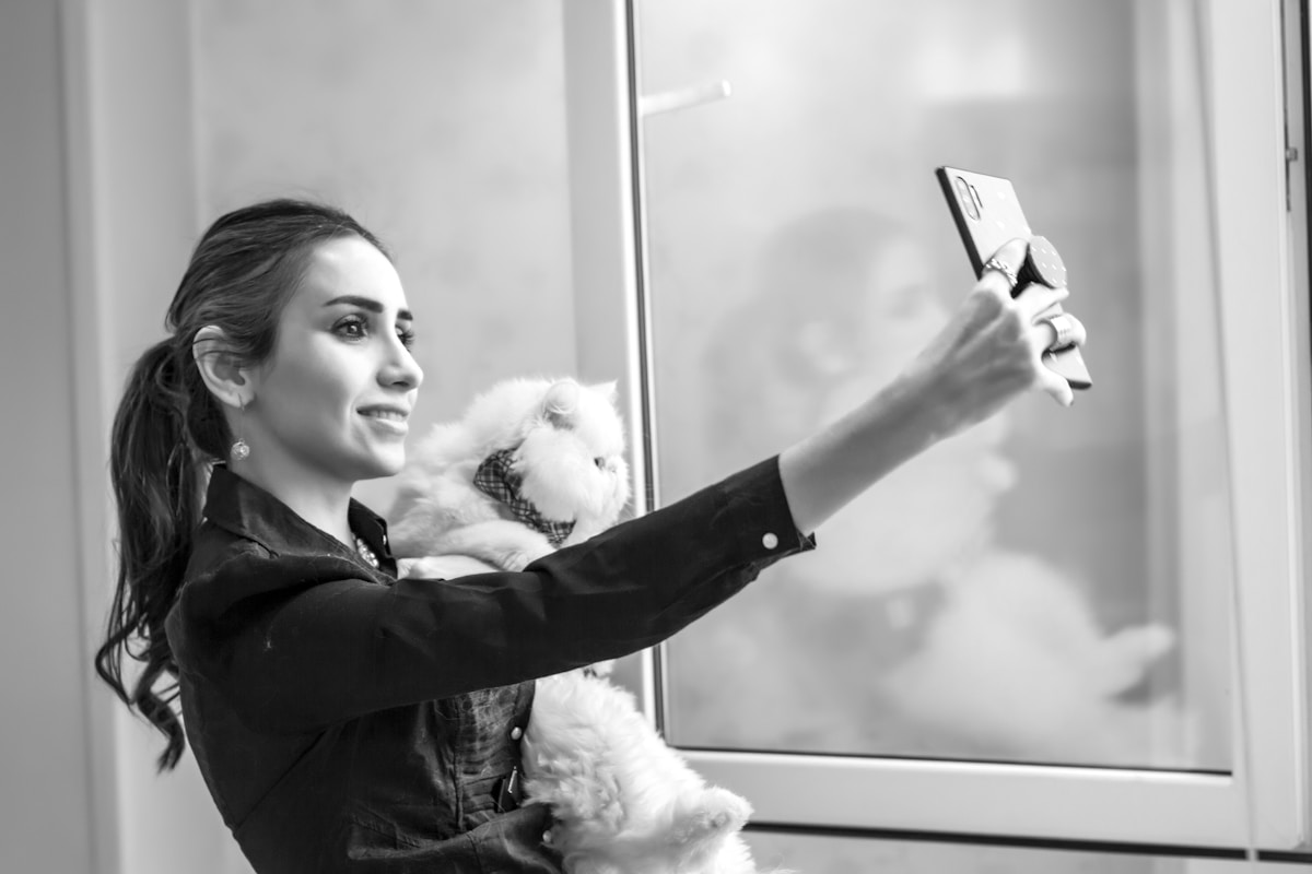 Femme prenant un selfie avec un chien blanc dans un bureau.