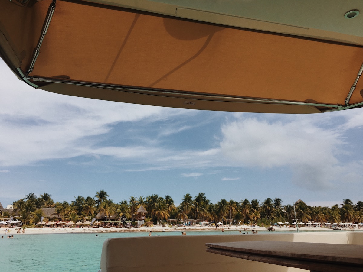 Plage tropicale avec palmiers, parasols et baignade dans l'eau turquoise.