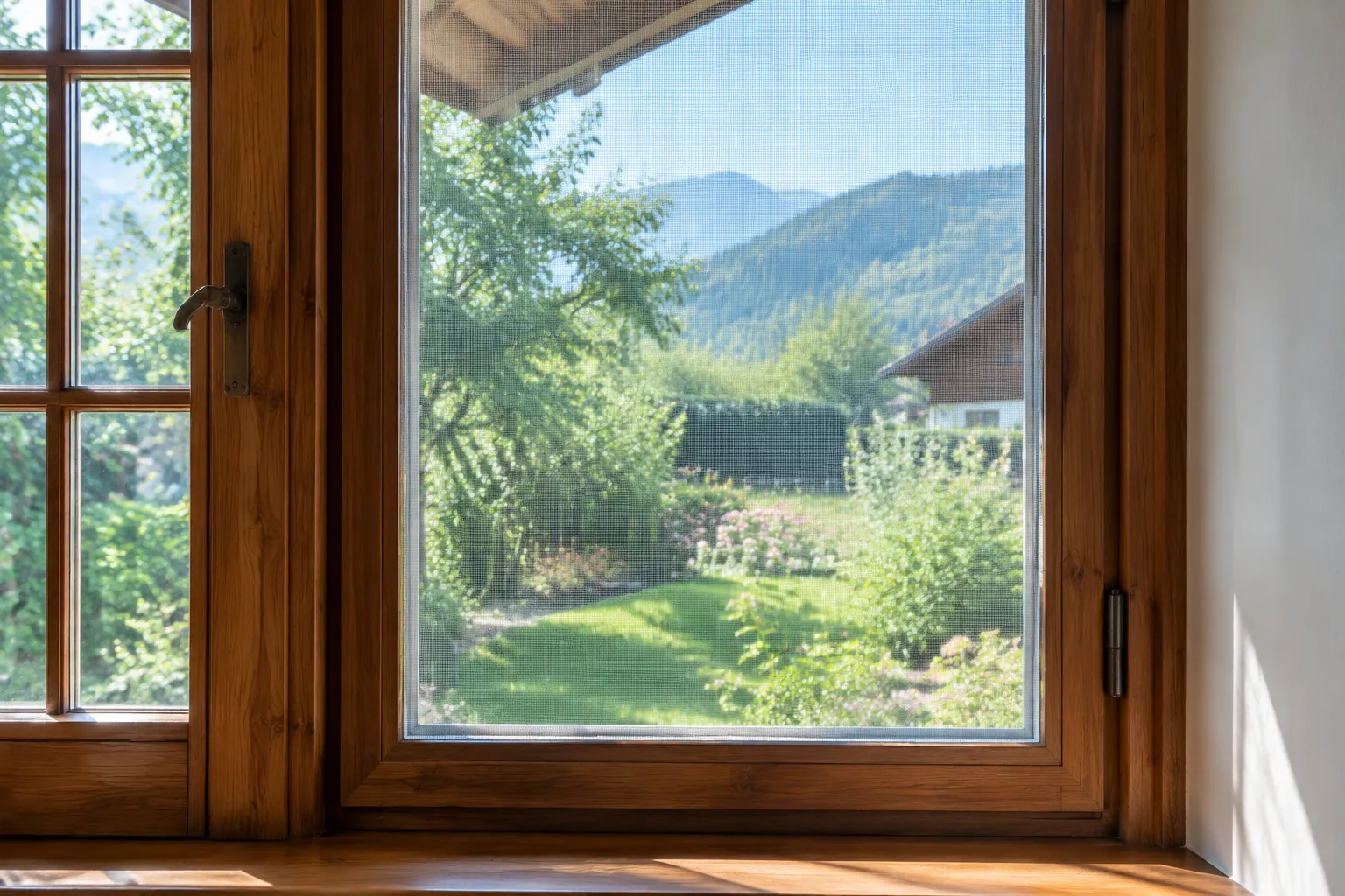 Moustiquaire en fil polyester tendue sur une fenêtre en bois, vue d’un jardin verdoyant.
