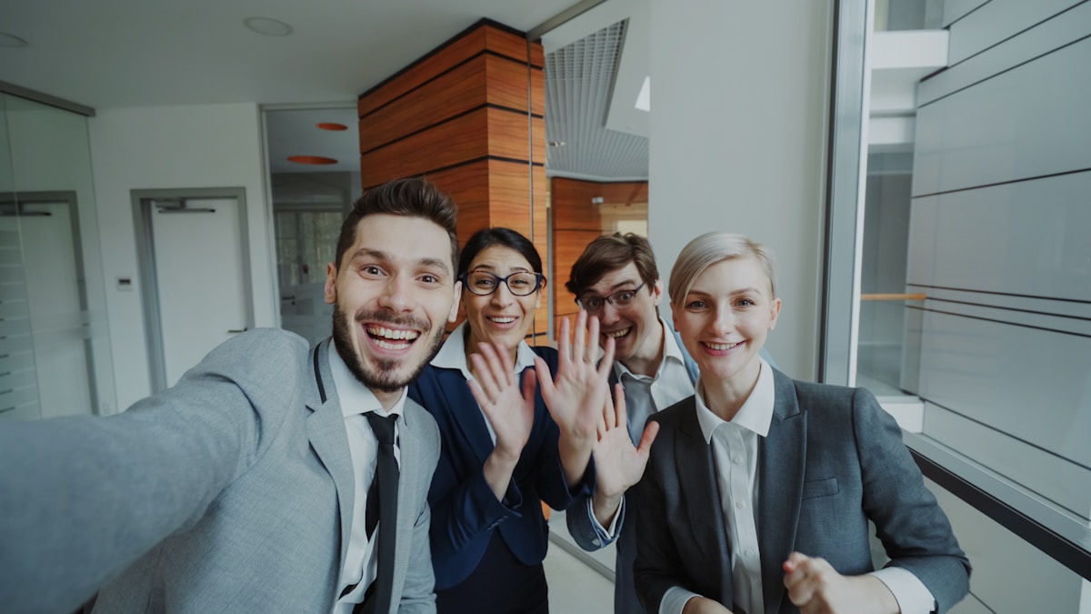 Groupe de collègues souriants et enthousiastes dans un bureau moderne.
