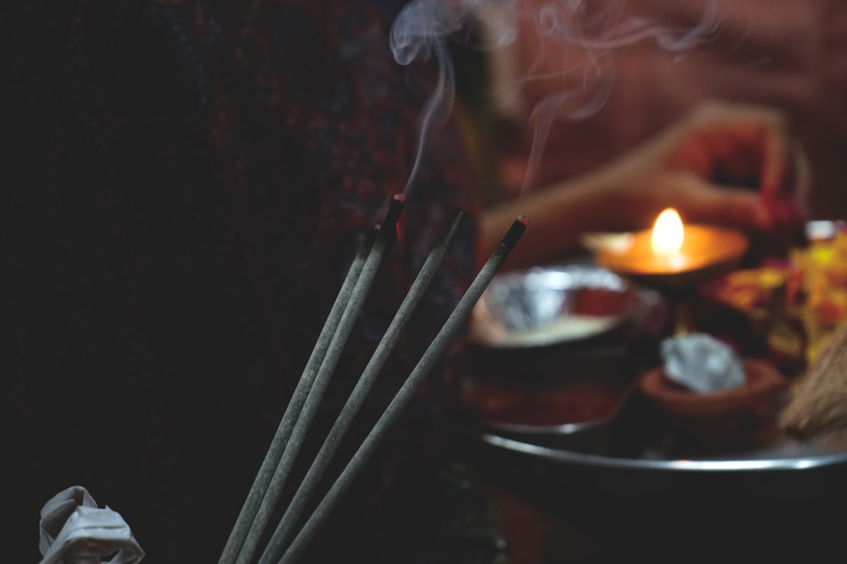 Bâtonnets d'encens fumants, bougie allumée, objets rituels mystiques.
