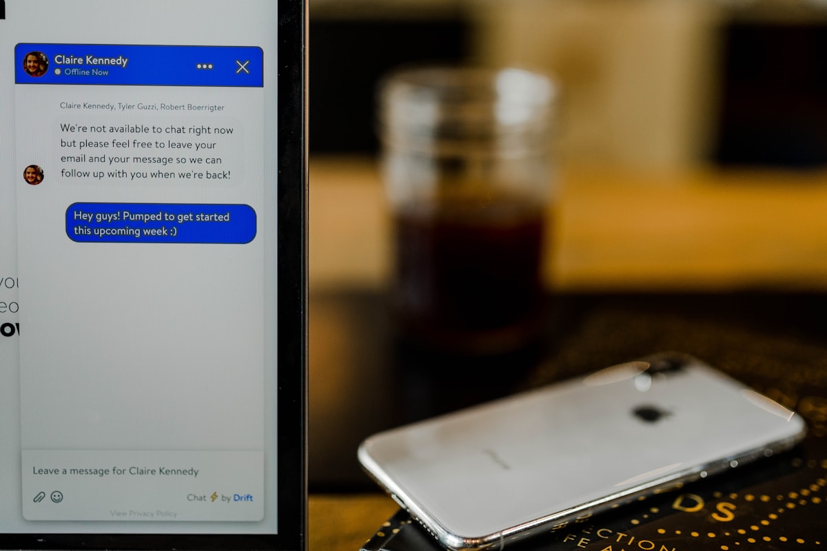 Écran de messagerie instantanée avec profil d'utilisateur et smartphone sur table.