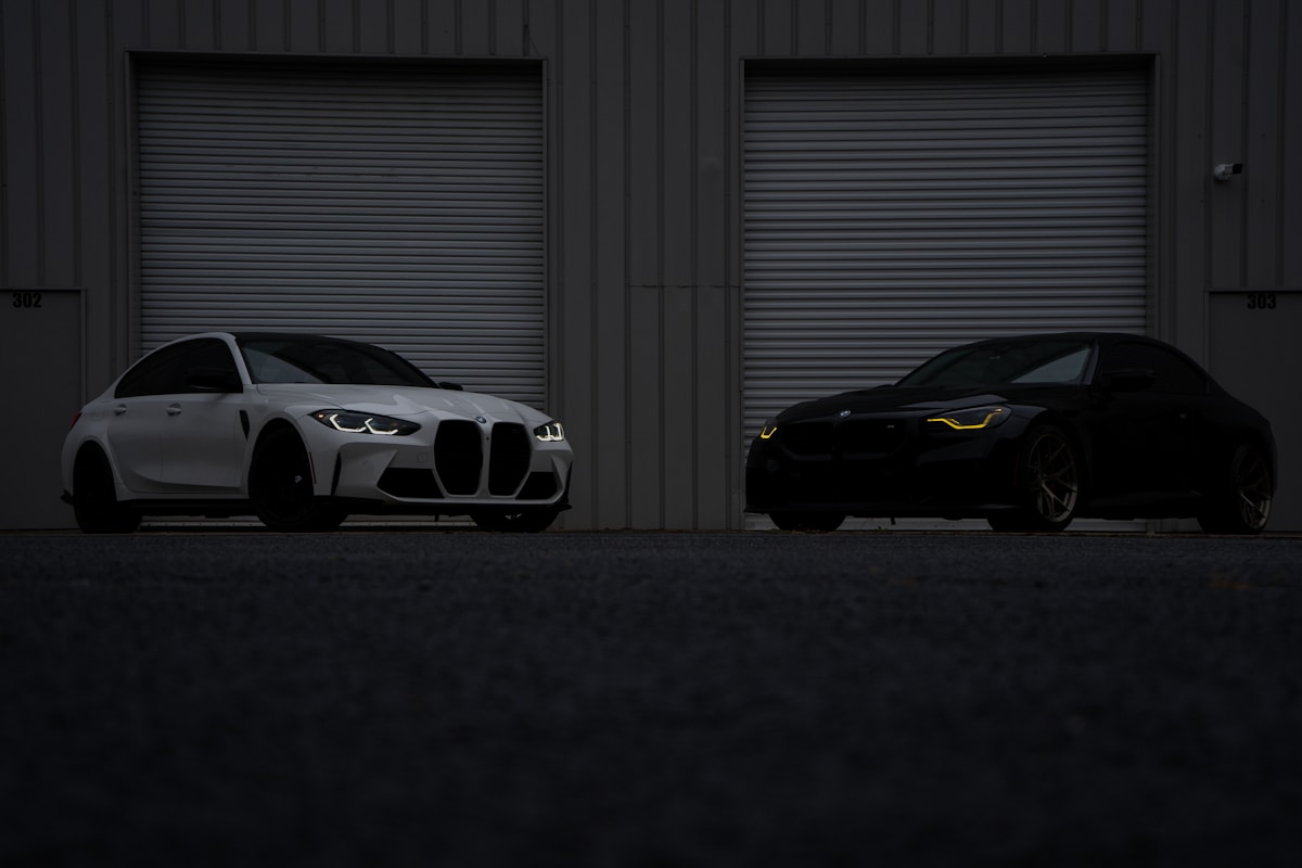 Deux voitures de luxe BMW dans un garage sombre.