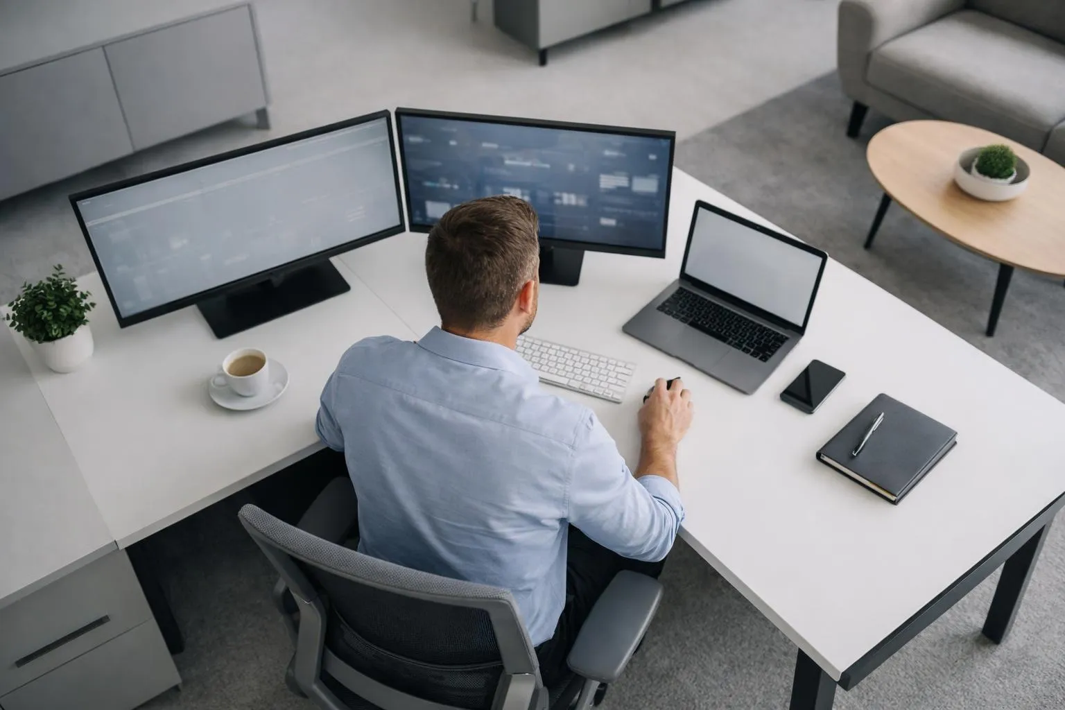 Homme travaillant sur plusieurs écrans d'ordinateur dans un bureau moderne.