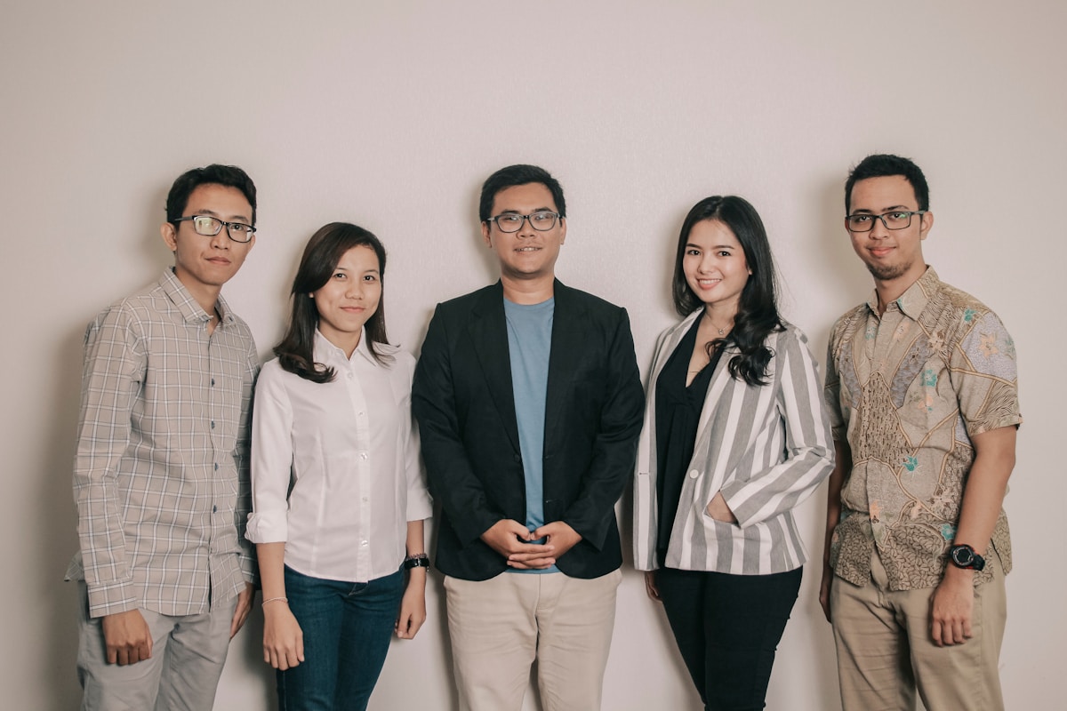 Groupe de cinq personnes souriantes, habillées de manière professionnelle.