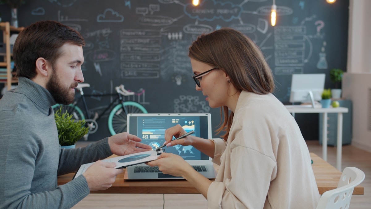 Deux personnes collaborant sur un projet informatique dans un espace de travail créatif.