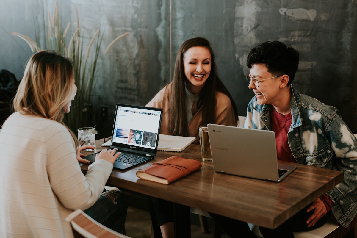 Trois jeunes amis travaillant ensemble sur leurs ordinateurs portables dans un café.
