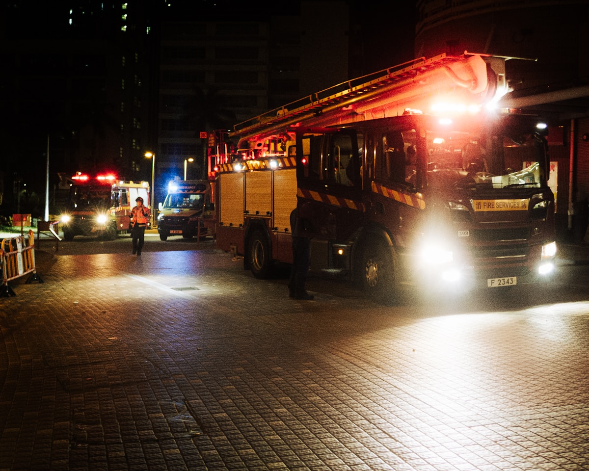 Camion de pompiers avec sirènes et éclairages d'urgence dans une rue sombre.