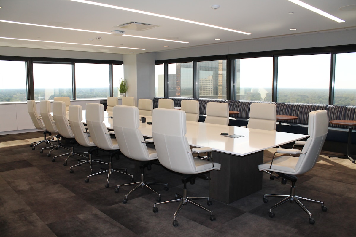 Salle de réunion moderne avec grandes fenêtres et mobilier blanc.