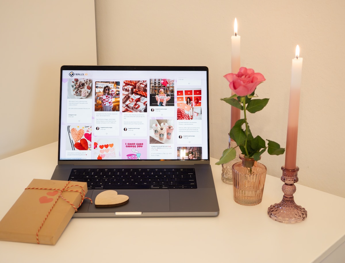 Bureau avec ordinateur portable, fleurs, bougies et décoration de la Saint-Valentin.