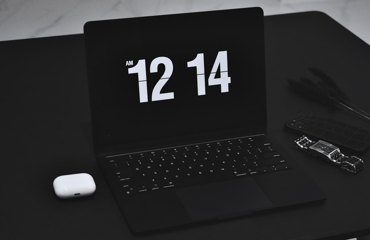 Ordinateur portable noir avec l'heure 12:14 affichée sur l'écran.