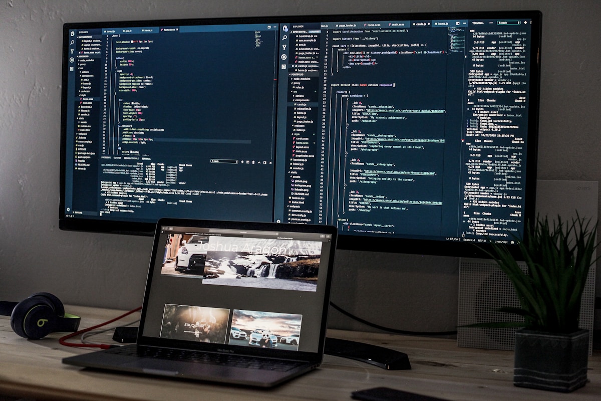 Poste de travail avec ordinateur portable, code source, casque audio et plante d'intérieur.