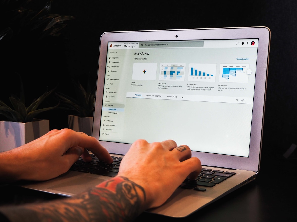 Ordinateur portable avec un tableau de bord analytique affiché à l'écran et des mains tatouées sur le clavier.