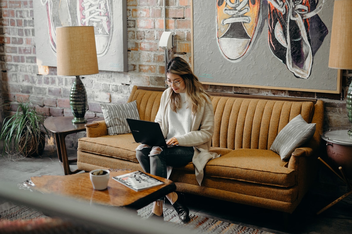 Jeune femme travaillant sur un ordinateur portable dans un salon confortable.
