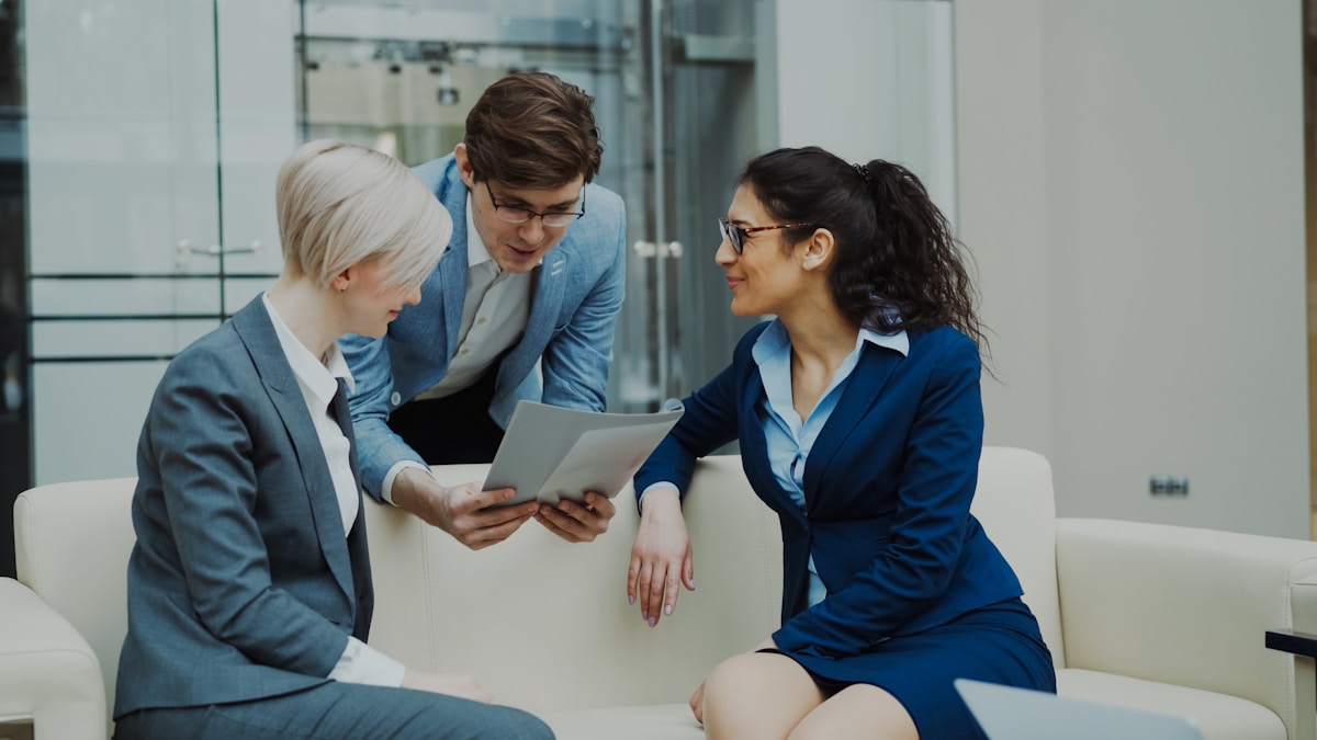 Trois professionnels en costume discutant de documents.