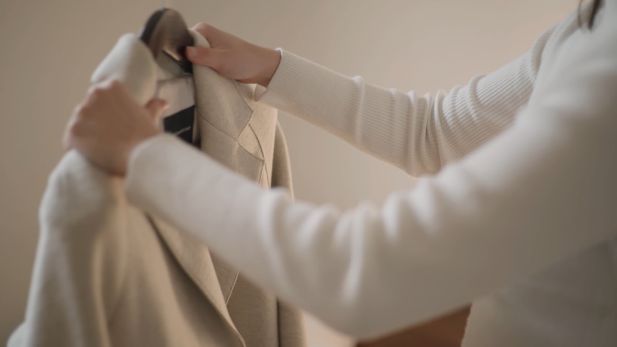 Gros plan sur des mains ajustant un vêtement beige.
