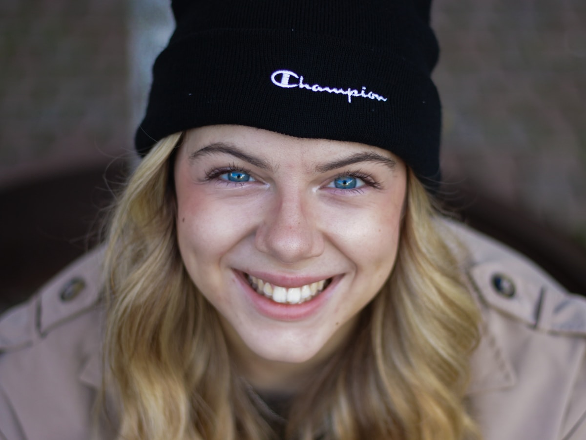 a woman wearing a black beanie smiles at the camera