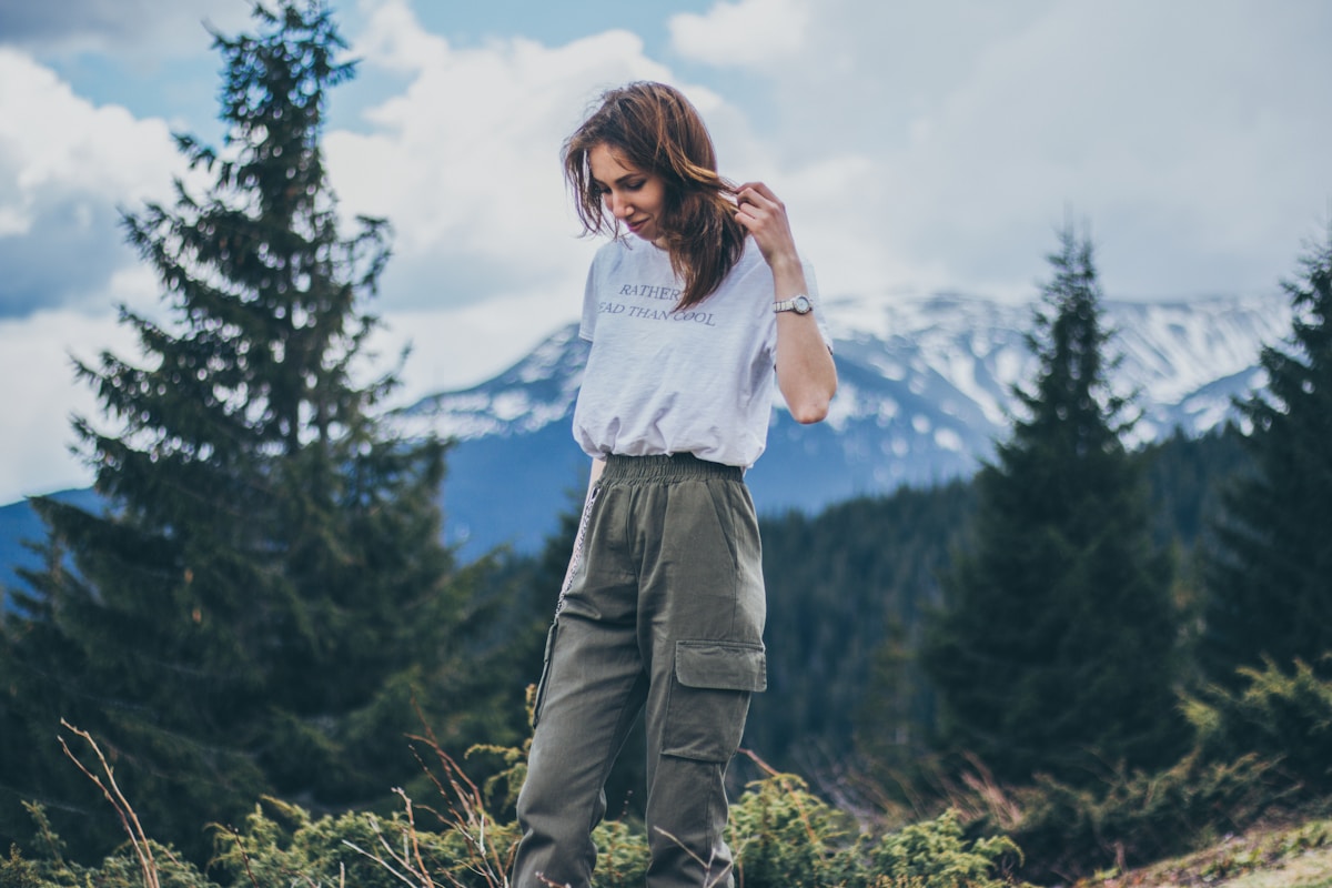 Femme dans un paysage montagneux avec un sweat à capuche et un pantalon cargo.