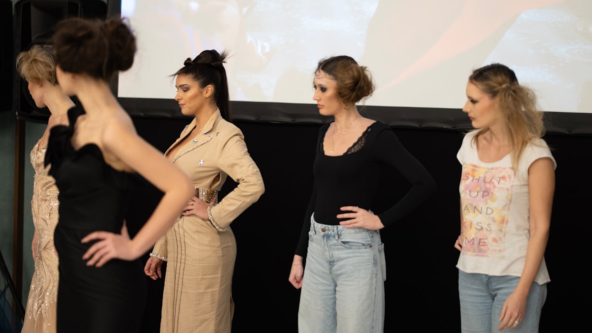 Quatre femmes posant sur une scène, vêtues de tenues élégantes et décontractées.