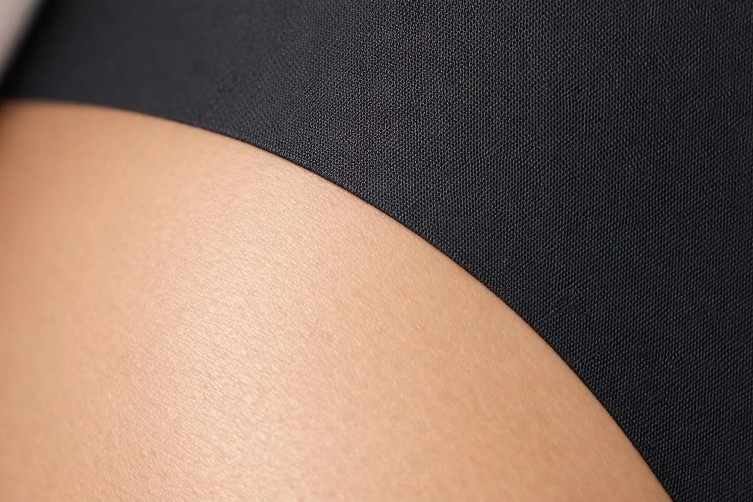 Extreme close-up photograph of seamless lingerie edge meeting skin, showing precise laser-cut technology with no visible stitching, smooth microfiber fabric texture, and zero demarcation line against natural skin tone, studio lighting emphasizing the invisible transition