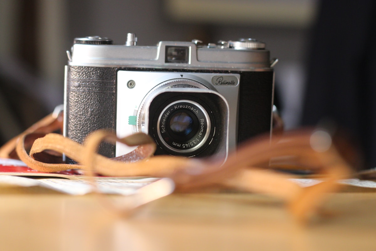 Un appareil photo DSLR noir et argent posé sur une table en bois brun.